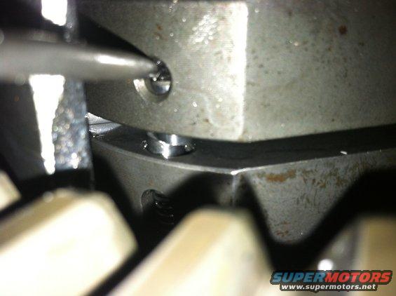 Close-up of metal gears with a screwdriver tip engaging a screw head