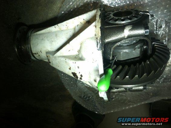 Differential housing with gears and a green tool, partially wrapped in plastic
