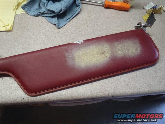 red car sun visor with some scuffs and a light spray paint mark