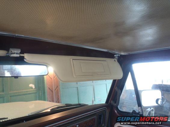 Interior view of a 1978 Ford Bronco showing a beige sun visor, rearview mirror, and dashboard trim