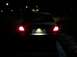 2008 Mercury Grand Marquis - The rear of a sedan is visible at night, with its brake lights and license plate light on.