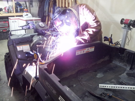 Black all-terrain vehicle with a person welding on it
