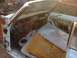 1964 Ford Ranchero - The interior of a classic car is shown with its doors open, revealing dismantled components and significant rust damage.