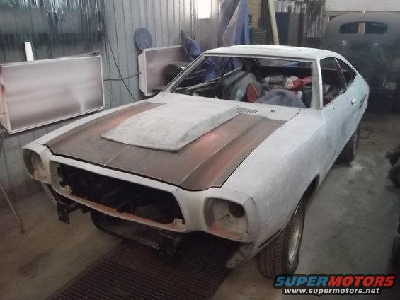 1978 Ford Mustang II body in primer with a hood scoop, in a workshop