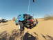 1970 Volkswagen Beetle - A modified blue Volkswagen Beetle is seen off-roading in a desert landscape with another vehicle in the background.