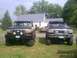 1994 Ford F-250 - Two lifted 1994 Ford F-250 trucks are parked in a grassy yard in front of a house.