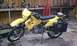 1989 Ford Bronco - A yellow Suzuki DR650 motorcycle is parked in a garage, equipped with saddlebags and a rear rack bag.