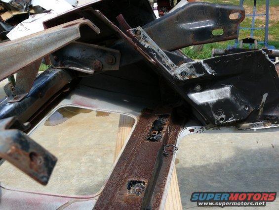 Rusted metal frame pieces and brackets, some with bolts, on a wooden surface