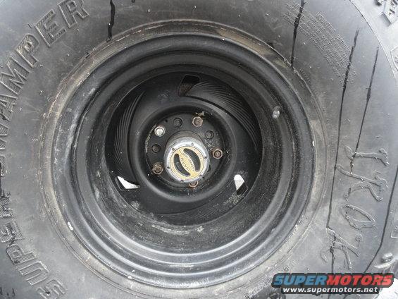 close-up of a vehicle's wheel and tire, showing a gold hubcap with text