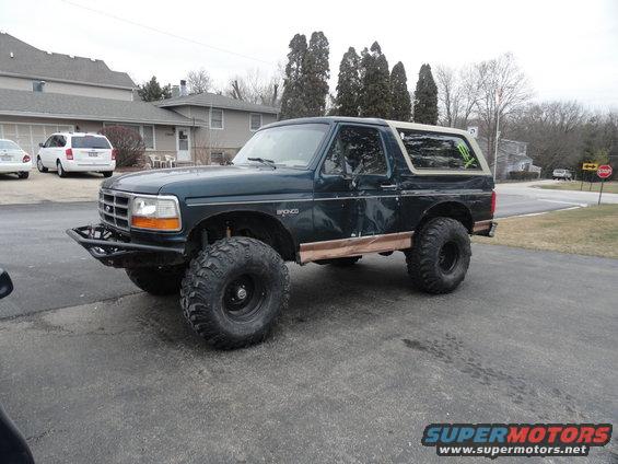 1995 Ford Bronco with aftermarket bumper and oversized tires parked on asphalt