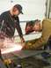 1990 Chevrolet Suburban - Two men are engaged in metalworking, one using an angle grinder while the other wears a welding mask, amidst a shower of sparks.