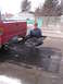 1994 Ford Bronco - A person kneels beside the rear of a red Toyota pickup truck, which is equipped with a cargo carrier and dual exhaust pipes.