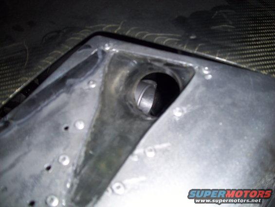 Close-up of a metal automotive part with a circular opening and visible rivets