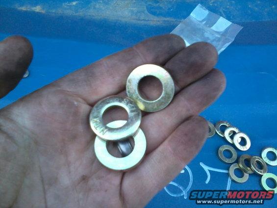 Hand holding several brass washers, some with visible markings