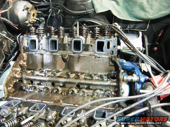 Close-up of a V8 engine block with the intake manifold off, showing the cylinder heads and valve train components