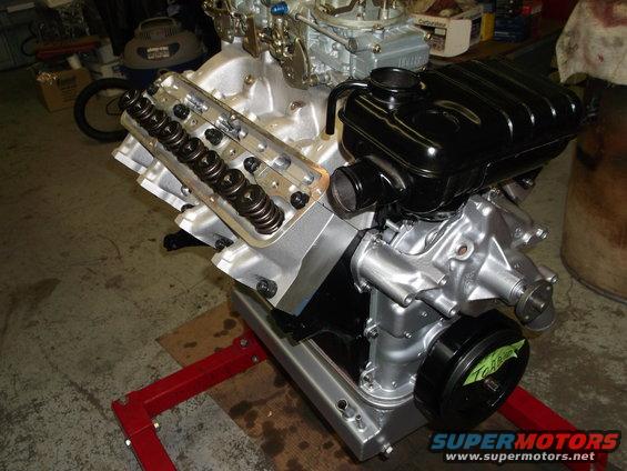 V8 engine with dual carburetors and black air cleaner assembly on a red engine stand