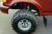 1995 Ford Bronco - Close-up of a red SUV's front wheel, showing a large off-road tire and suspension components.