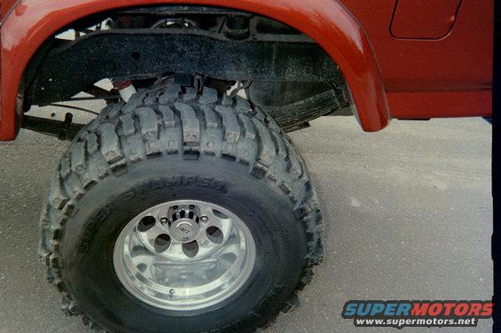 Red SUV's front fender and large off-road tire with chrome rim