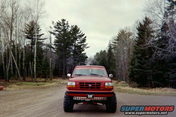 Red 1995 Ford Bronco front view with lifted suspension and CAT license plate
