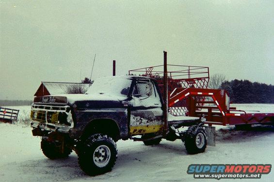 1976 Ford F-100 truck with a gooseneck trailer, covered in snow
