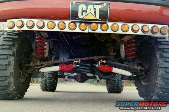 Rear view of a lifted truck showing its suspension, shocks, and a CAT license plate frame