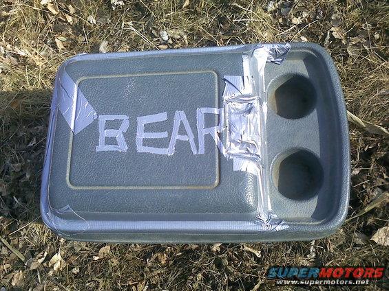 Gray plastic console with 'BEAR' written in white tape and two cup holders. Some silver tape is used to hold it together