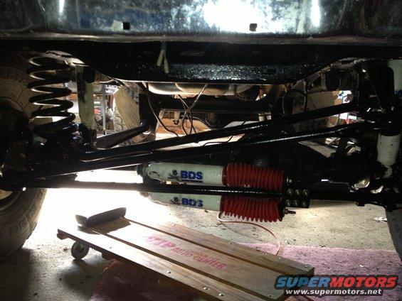 Undercarriage view showing suspension components and shocks with BDS branding. A wooden creeper is on the ground