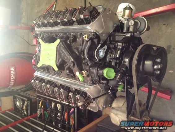 V8 engine with black block, silver valve covers, and green caps on hoses