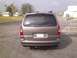 2005 Chevrolet Venture - The rear of a gold Chevrolet Venture minivan is shown parked on a paved surface with buildings in the background.