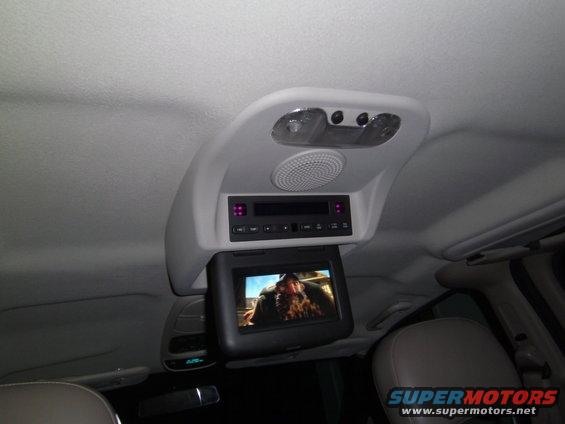 overhead screen showing a movie, with audio controls and lights above it