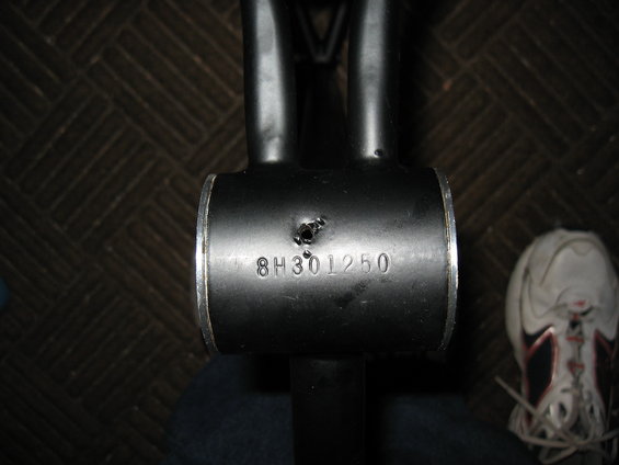Black metal tube with stamped serial number 8H301250 and a small hole