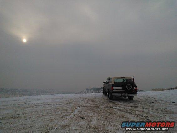 1992 Ford Bronco parked on a snowy landscape under a hazy sun