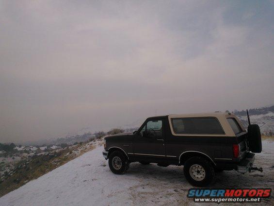 Ford Bronco parked on a snowy hill with a cloudy sky