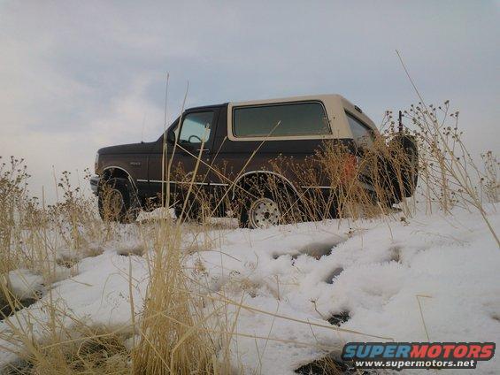 Brown 1992 Ford Bronco parked in a snowy field with dry grass