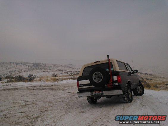 1992 Ford Bronco on a snowy road, spare tire mounted on the back, jack visible