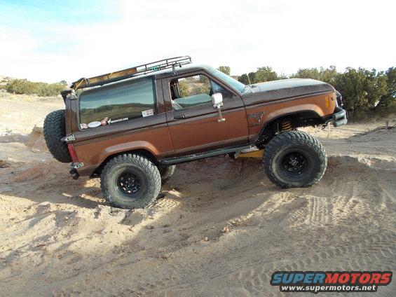 Brown 1986 Ford Bronco II with large tires on a sandy trail