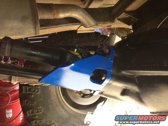 Undercarriage of a vehicle showing a blue suspension part, exhaust pipe, and tire tread