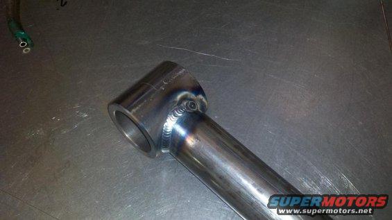 Welded metal tube with a flange on one end, resting on a metal surface