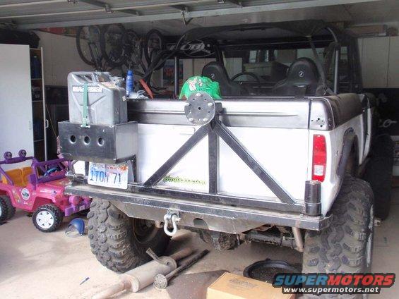 rear view of white SUV with large tires, jerry can, and spare tire mount. Pink toy Jeep nearby
