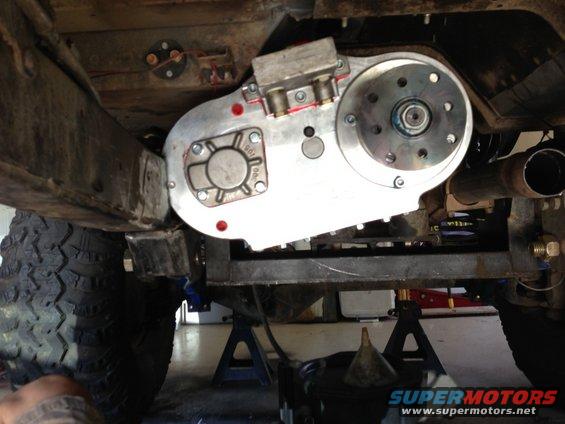 underbody view of a vehicle's transfer case with aftermarket modifications, supported by jack stands