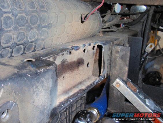 Close-up of a dirty vehicle frame with a tire and wiring visible