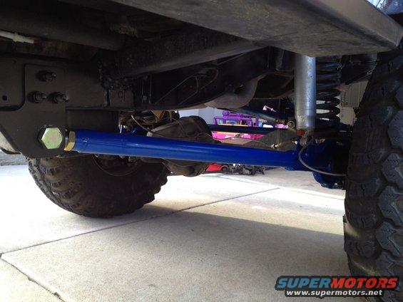 Undercarriage view showing blue radius arms and a silver shock absorber on a vehicle with large tires