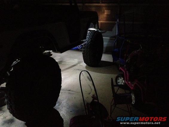 1971 Ford Bronco fender and large off-road tire illuminated by rock lights