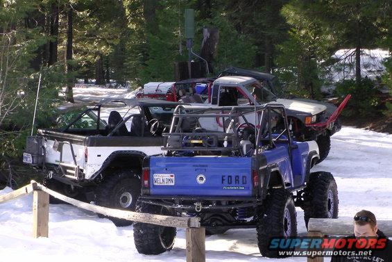 Blue 1971 Ford Bronco rear view in snow, white Bronco behind it