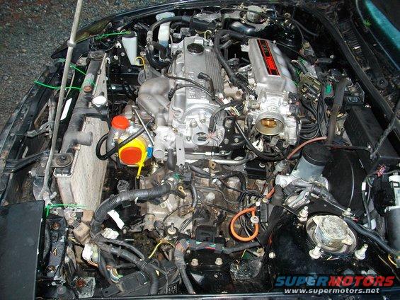 Engine bay view of a V6 engine with turbocharger and radiator visible
