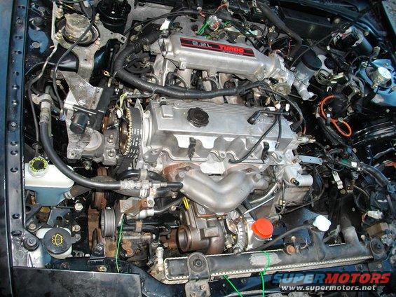 engine bay with 2.2L turbo engine, hoses, wires, and radiator visible