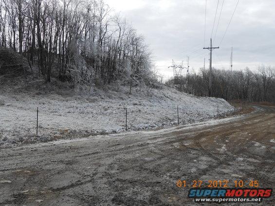 Icy trees line a muddy dirt road with power lines overhead
