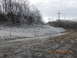 1986 Ford Bronco - A winter scene shows trees covered in ice next to a muddy, unpaved road under a cloudy sky.