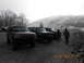 1986 Ford Bronco - A group of SUVs, including a Ford Bronco, are parked outdoors on a cloudy day with a mountain range in the distance.