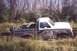 1988 Ford Bronco - This Ford Bronco is deeply stuck in mud and vegetation, with trees forming a dense backdrop.